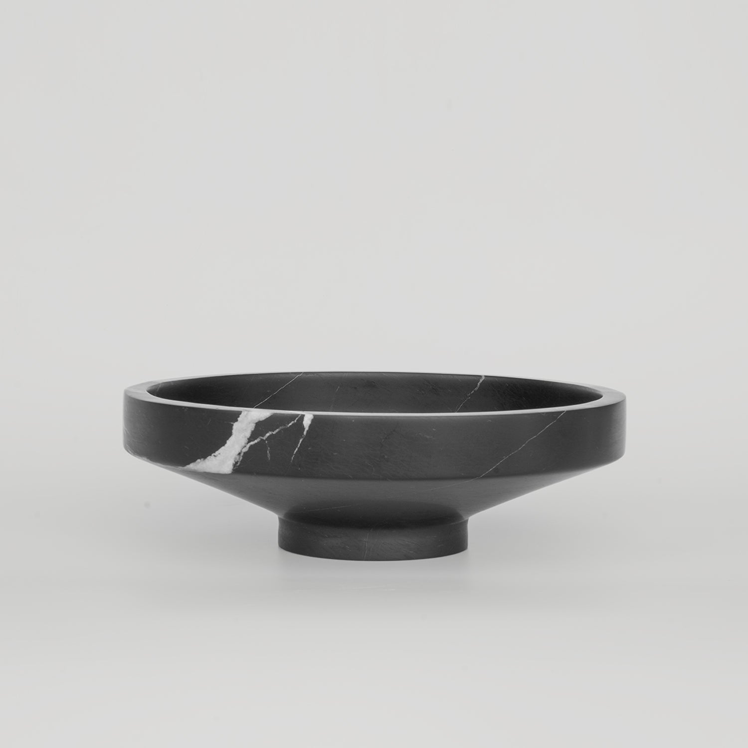 Black marble bowl with sculptural round shape and veined surface