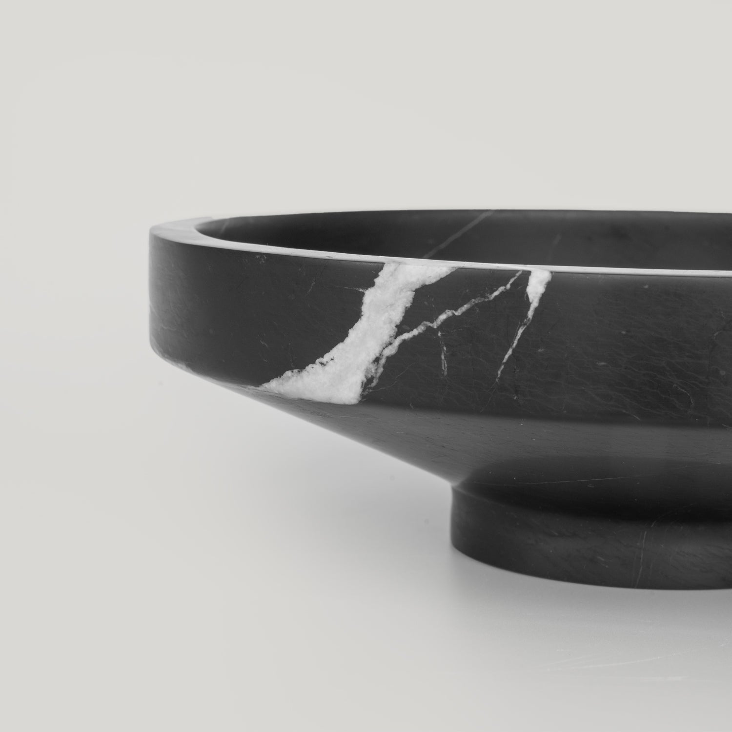 Black marble bowl with sculptural round shape and veined surface