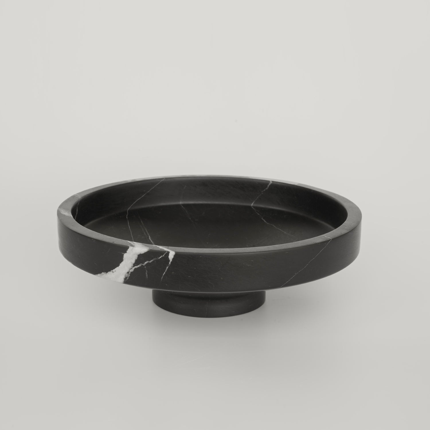Black marble bowl with sculptural round shape and veined surface