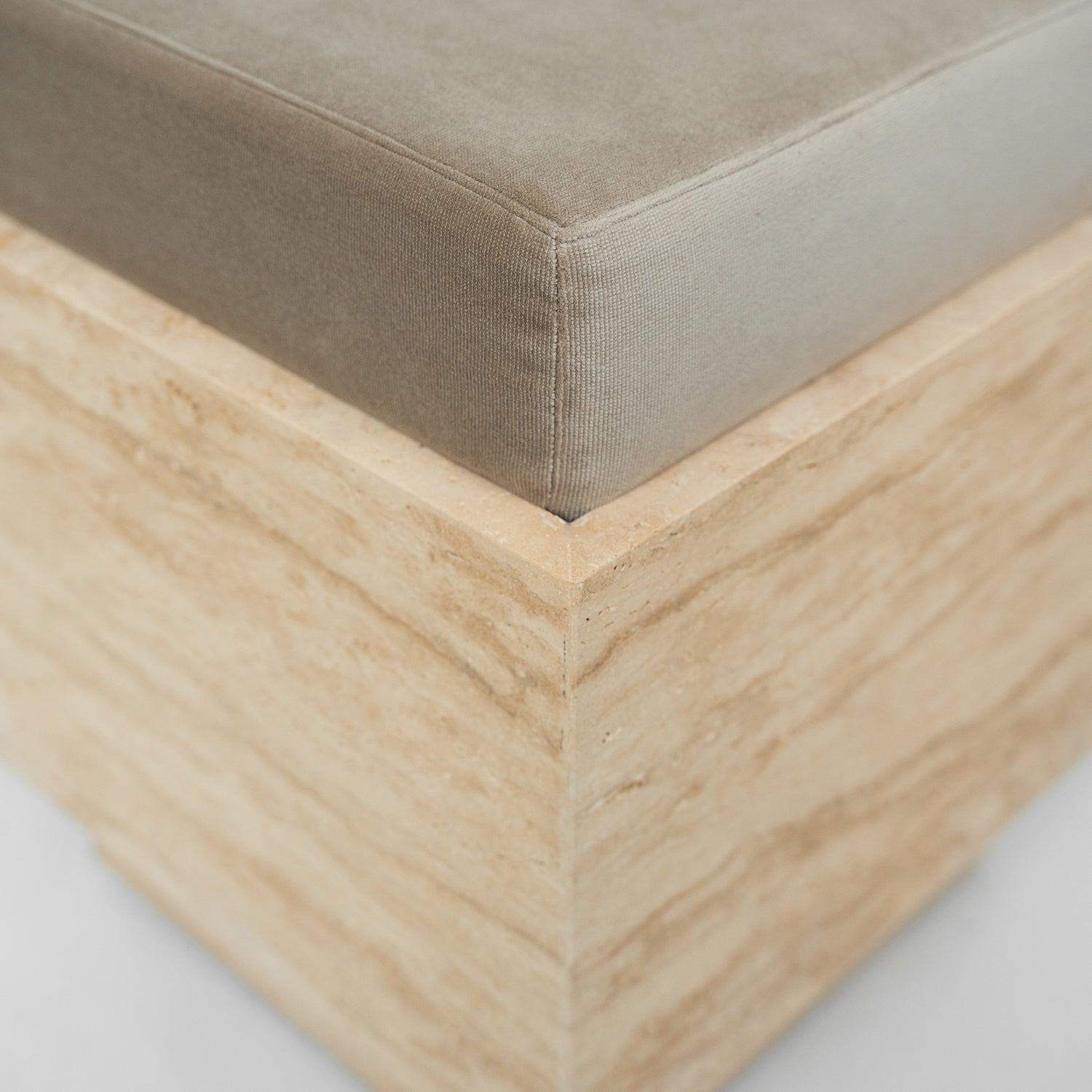 Travertine cube stool with velvet cushion in modern setting