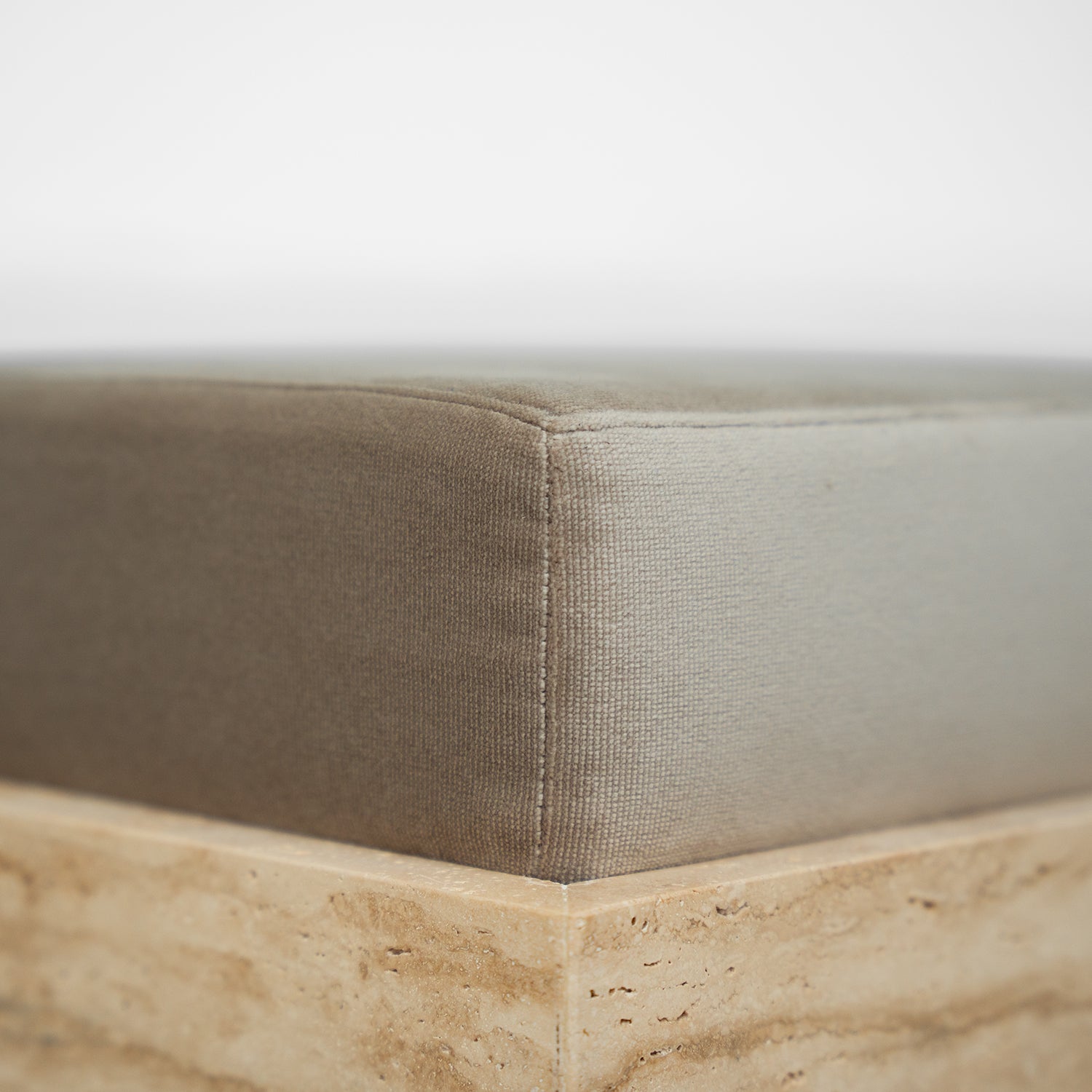 Travertine cube stool with velvet cushion in modern setting