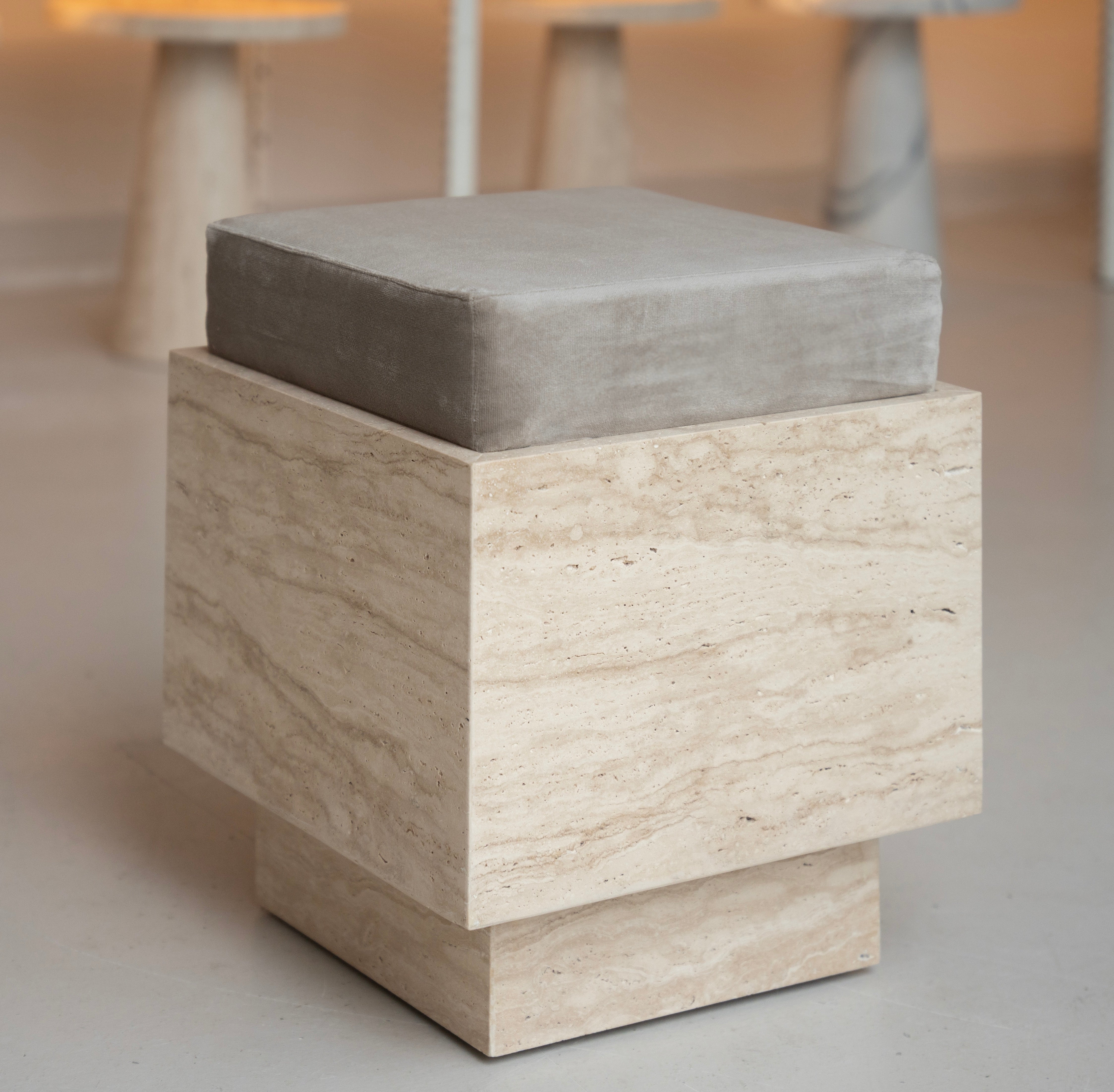 Travertine cube stool with velvet cushion in modern setting