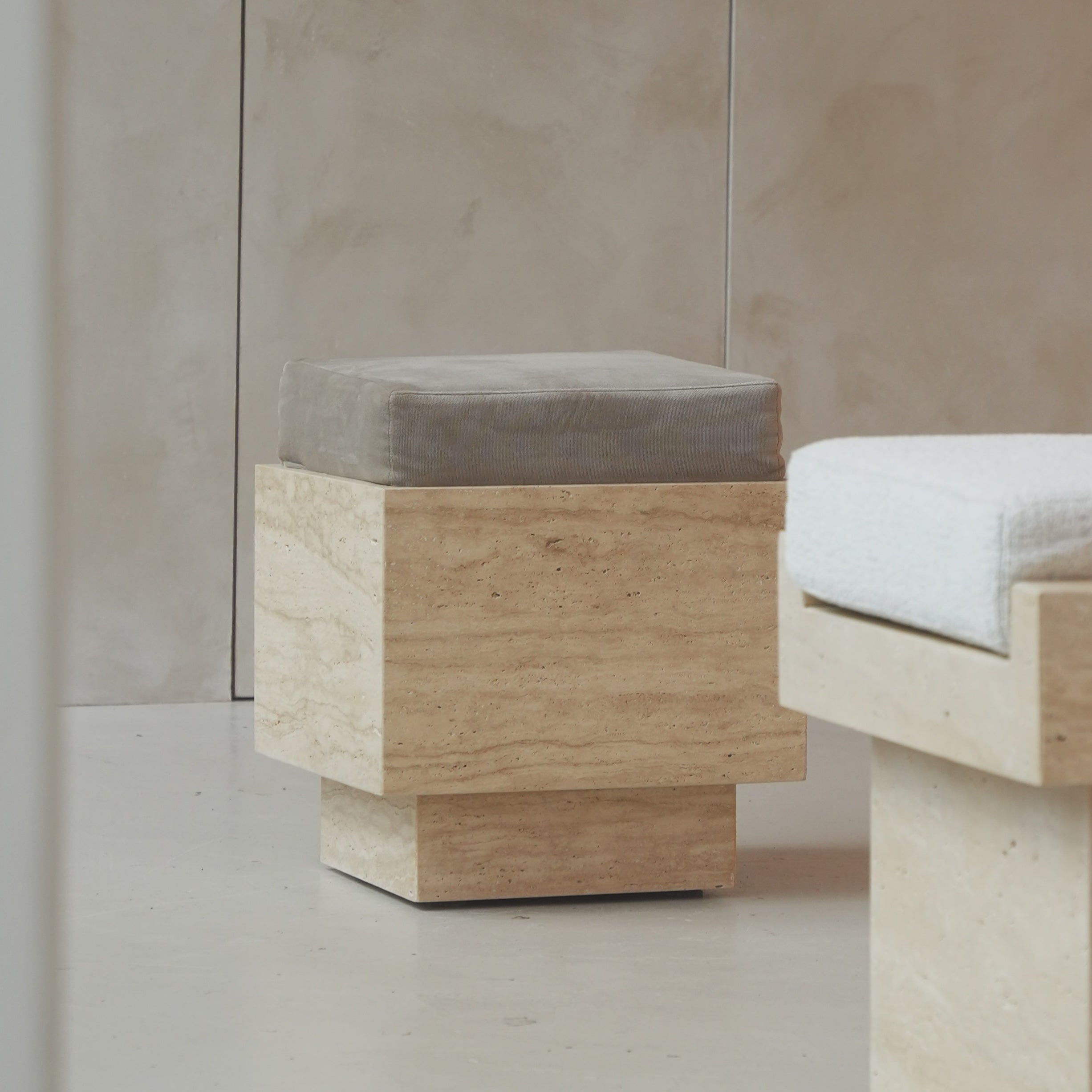 Travertine cube stool with velvet cushion in modern setting