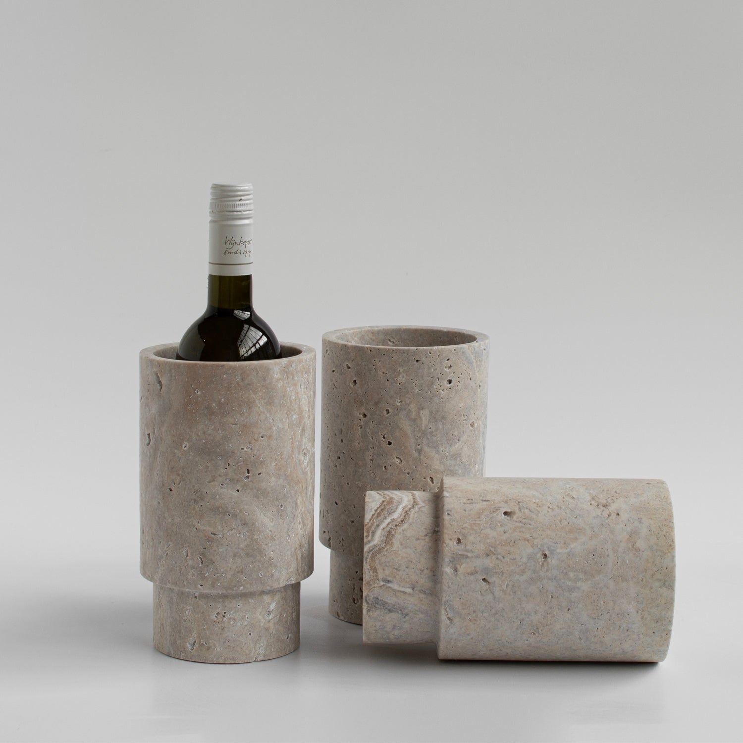 Silver travertine vase and wine bottle holder on table