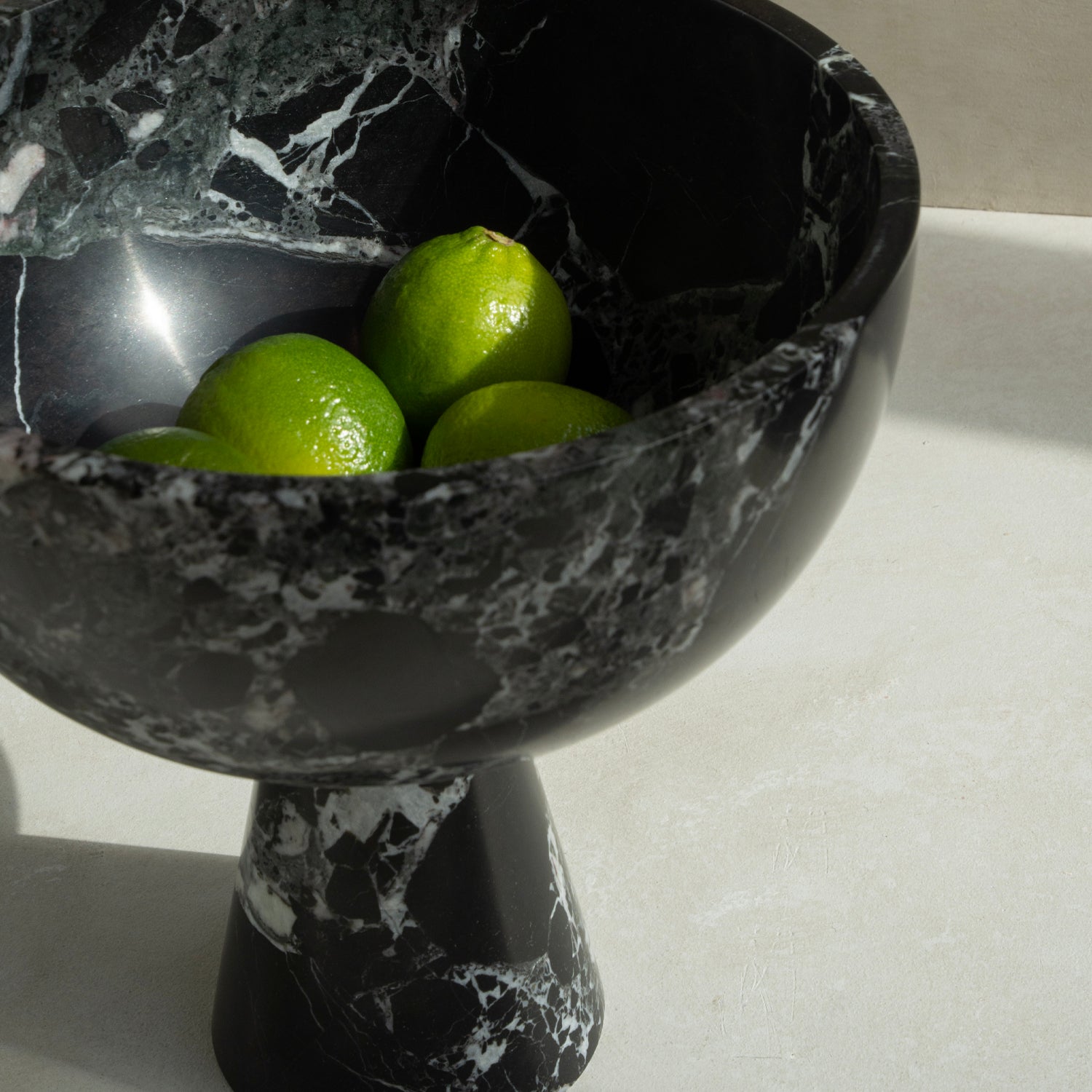 Black marble pedestal bowl with green marble veins
