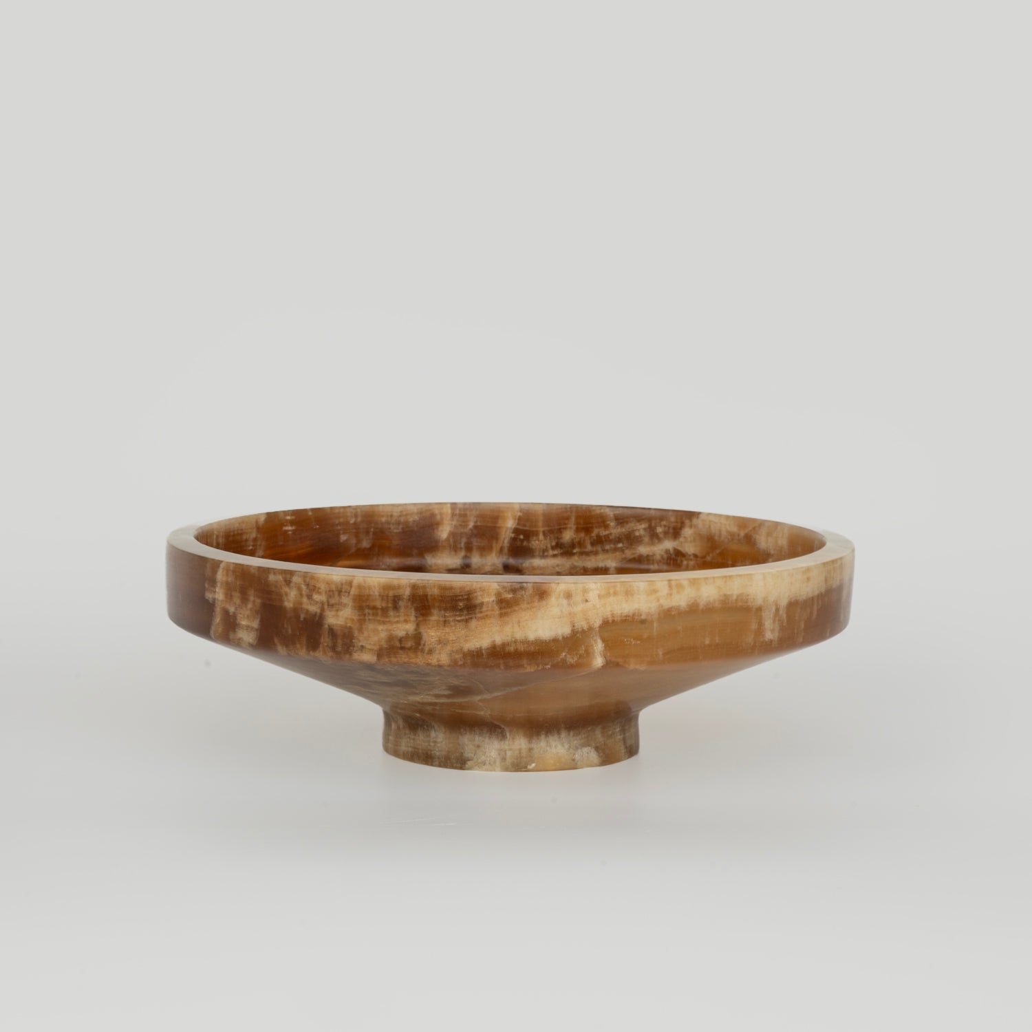 Onyx bowl with natural veining on white stone surface